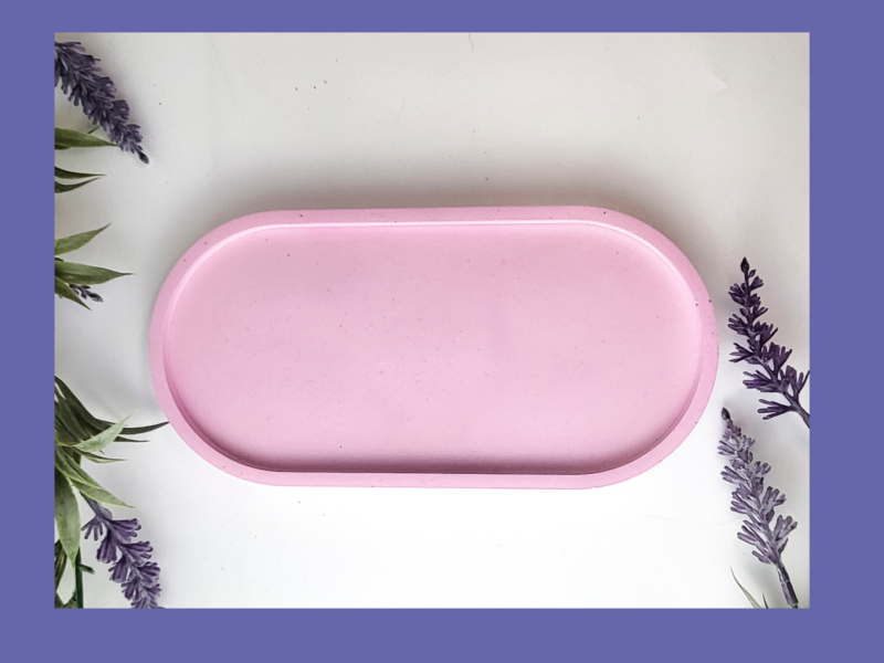 Pink Oval Decorative tray against a white background with some lavender flowers framing it